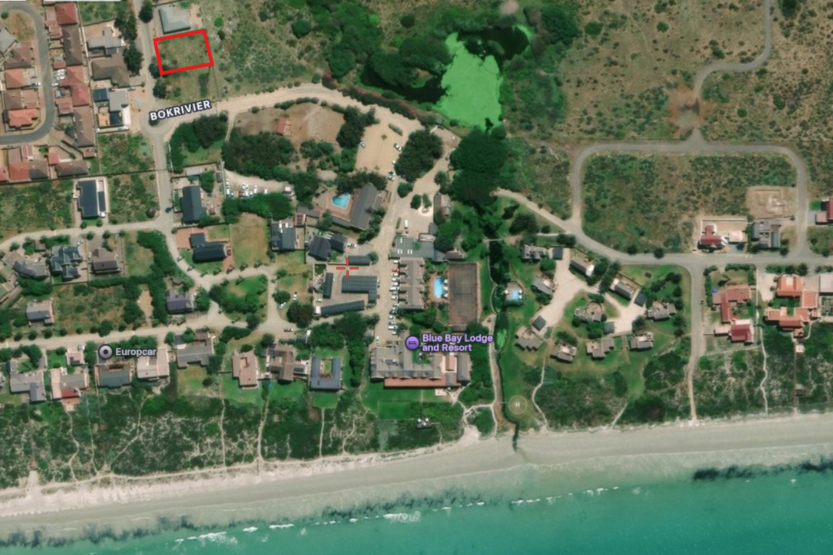 Aerial view showing the vacant residential plot highlighted in red, situated within a coastal estate near the beach and resort facilities.