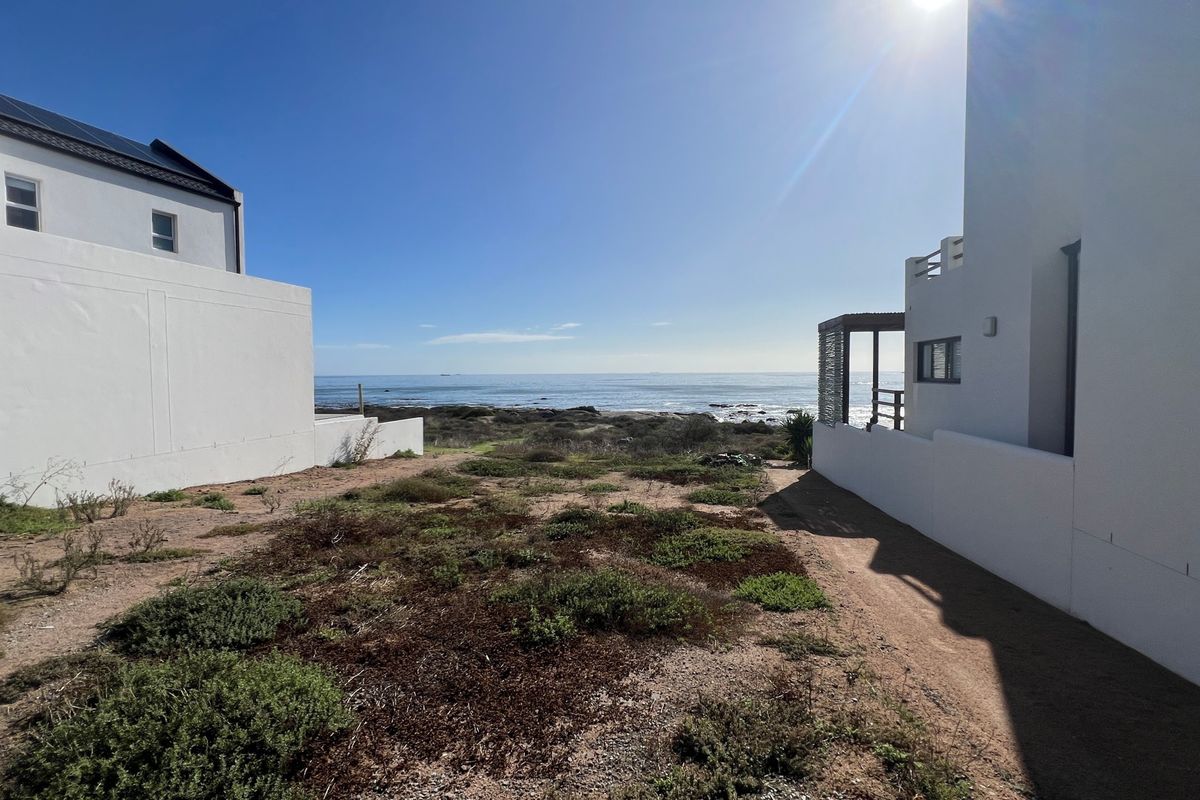 A clear view of the ocean from between two residential properties, showcasing the coastal landscape and natural terrain.