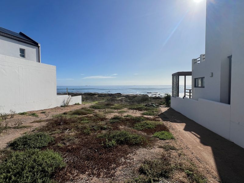 A clear view of the ocean from between two residential properties, showcasing the coastal landscape and natural terrain.