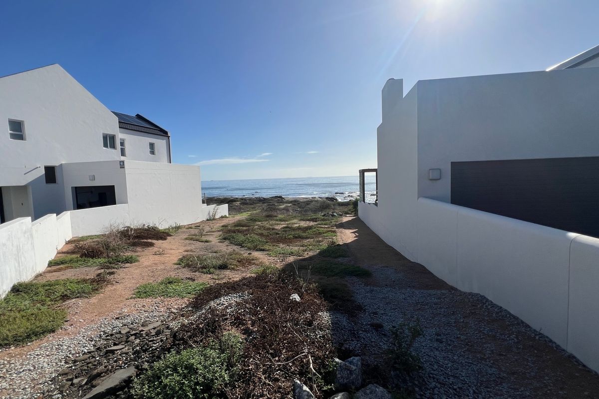 A view of the ocean from between two residential properties, showcasing the coastal location and surrounding landscape.