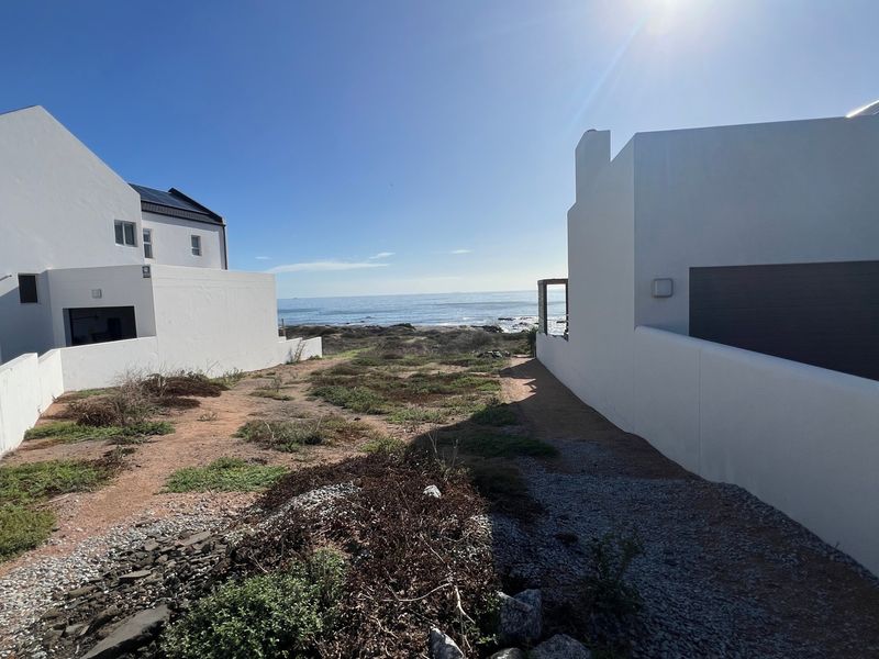 A view of the ocean from between two residential properties, showcasing the coastal location and surrounding landscape.