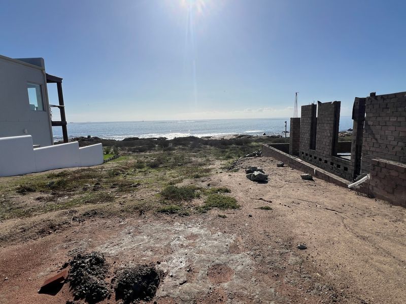 Vacant residential land featuring an ocean view and partially constructed masonry walls, offering a prime opportunity for development in a coastal setting.