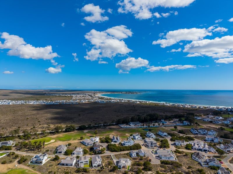 An aerial view of a coastal residential estate, showcasing the surrounding landscape, proximity to the ocean, and the layout of the neighborhood.