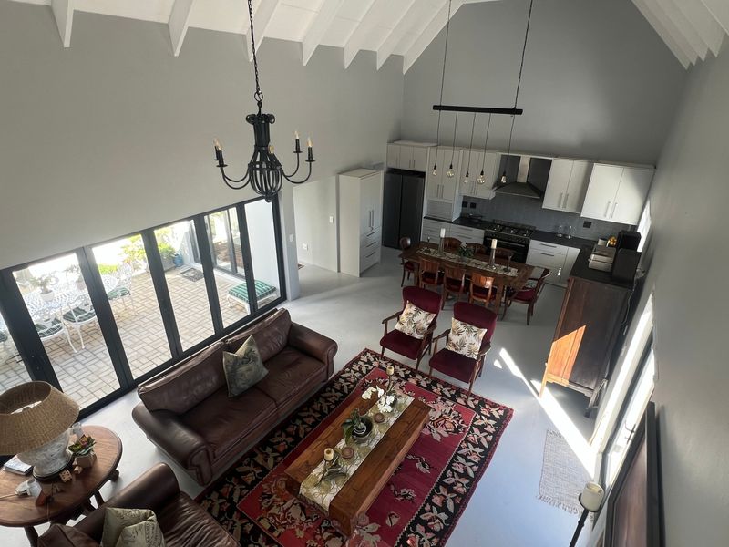 Spacious open-plan living and kitchen area featuring a high vaulted ceiling, modern cabinetry, and large bi-fold doors opening to an outdoor patio.