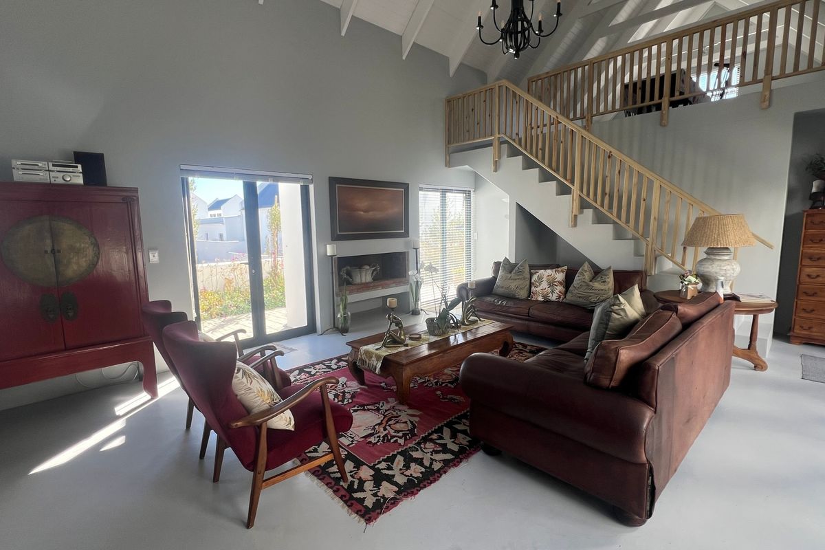 Spacious living room featuring a vaulted ceiling, a built-in fireplace, and a staircase with a wooden balustrade, finished with polished concrete flooring.