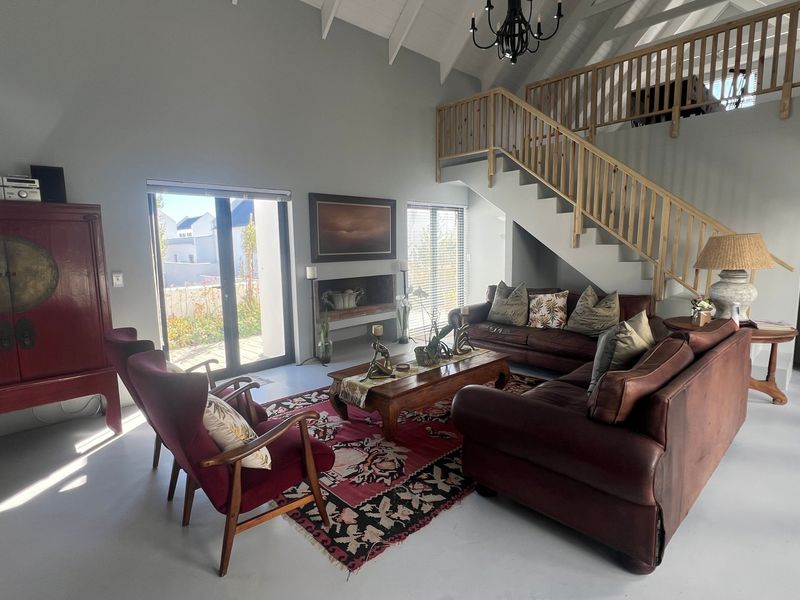 Spacious living room featuring a vaulted ceiling, a built-in fireplace, and a staircase with a wooden balustrade, finished with polished concrete flooring.