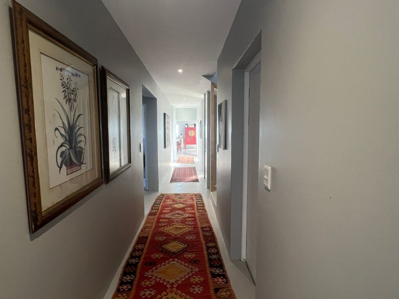 A well-lit interior hallway featuring neutral wall finishes, recessed downlighting, and multiple internal door access points.
