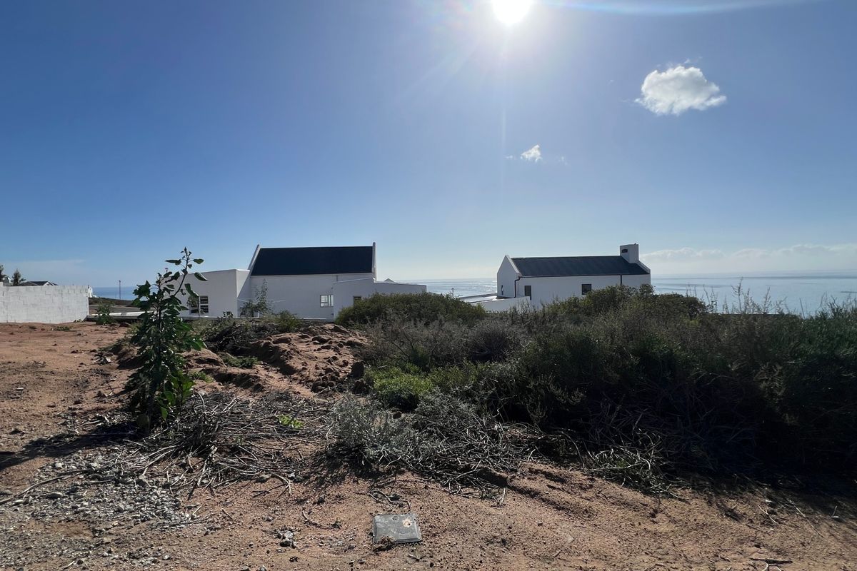 A view of the vacant residential land with coastal scenery and neighboring properties in the distance.