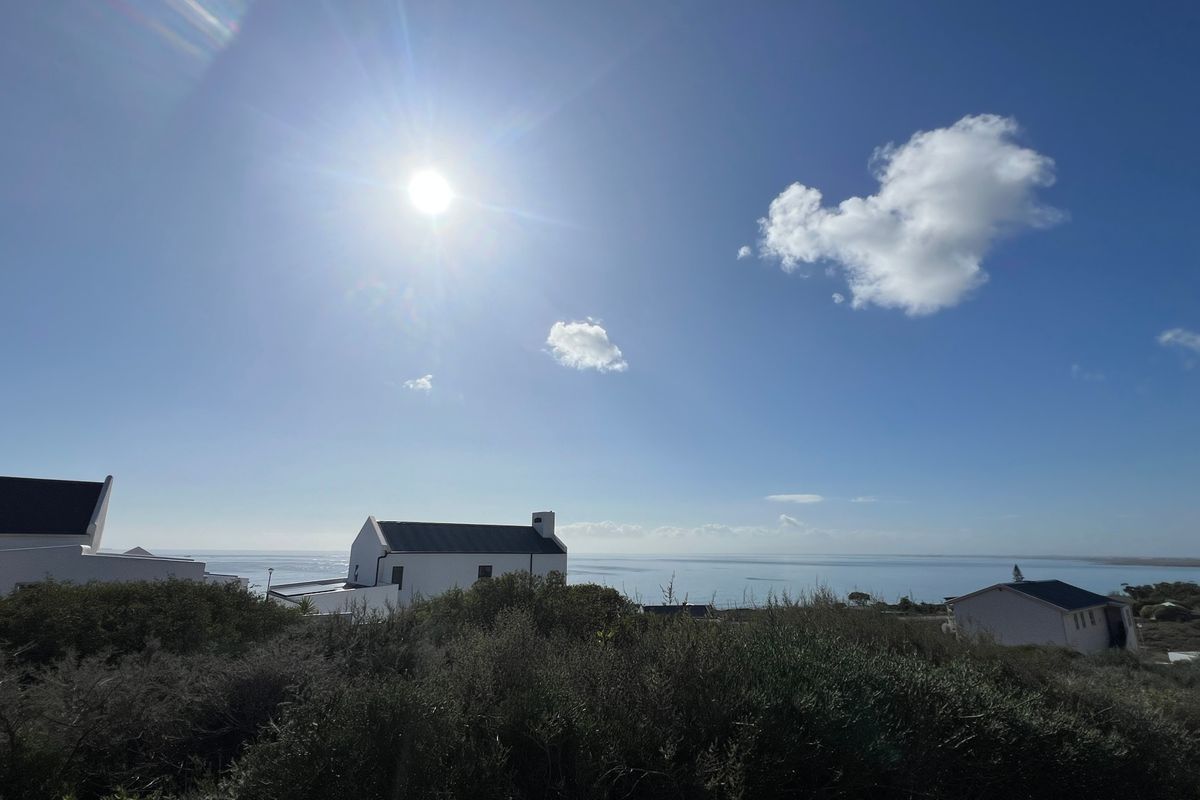 A scenic elevated view overlooking the coastline and surrounding residential properties under a bright sunny sky.
