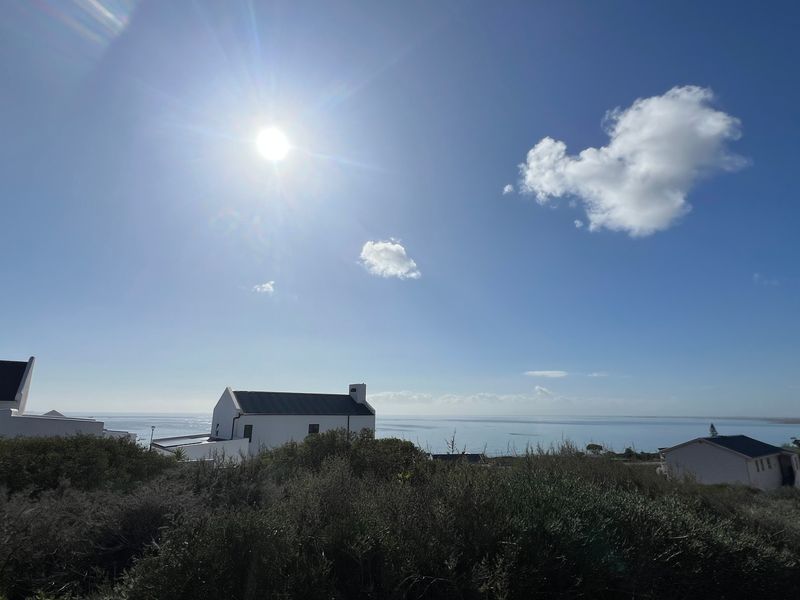 A scenic elevated view overlooking the coastline and surrounding residential properties under a bright sunny sky.