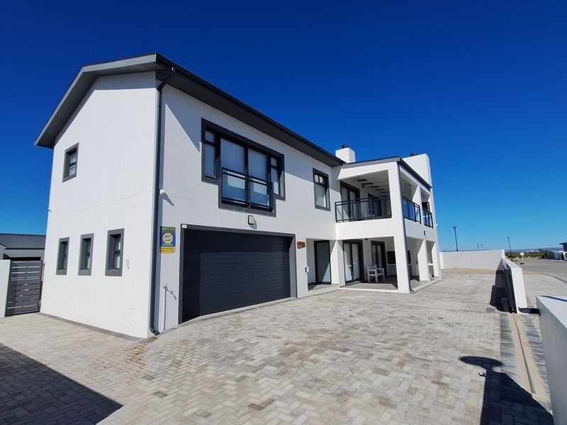 Modern double-story residential property featuring a paved driveway, integrated double garage, and upper-level balcony with clean architectural lines.