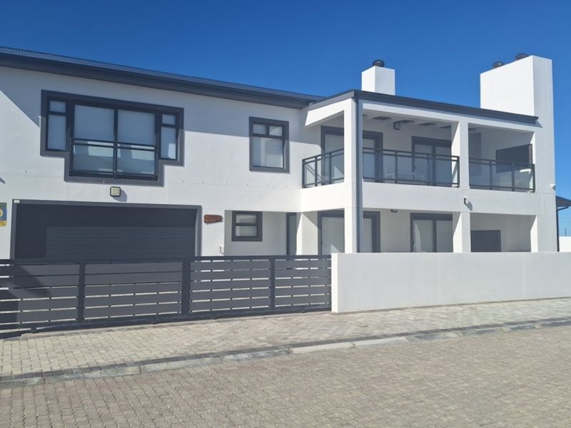 Modern double-story house featuring a clean white facade, dark window frames, a double garage, and a spacious upper-level balcony.