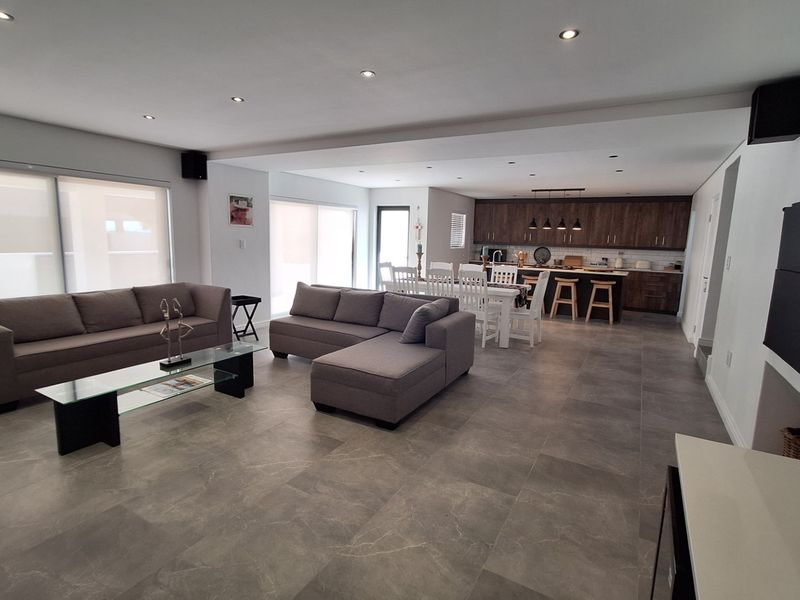 Spacious open-plan living and dining area featuring modern porcelain floor tiles, recessed lighting, and a contemporary kitchen with integrated cabinetry and island.