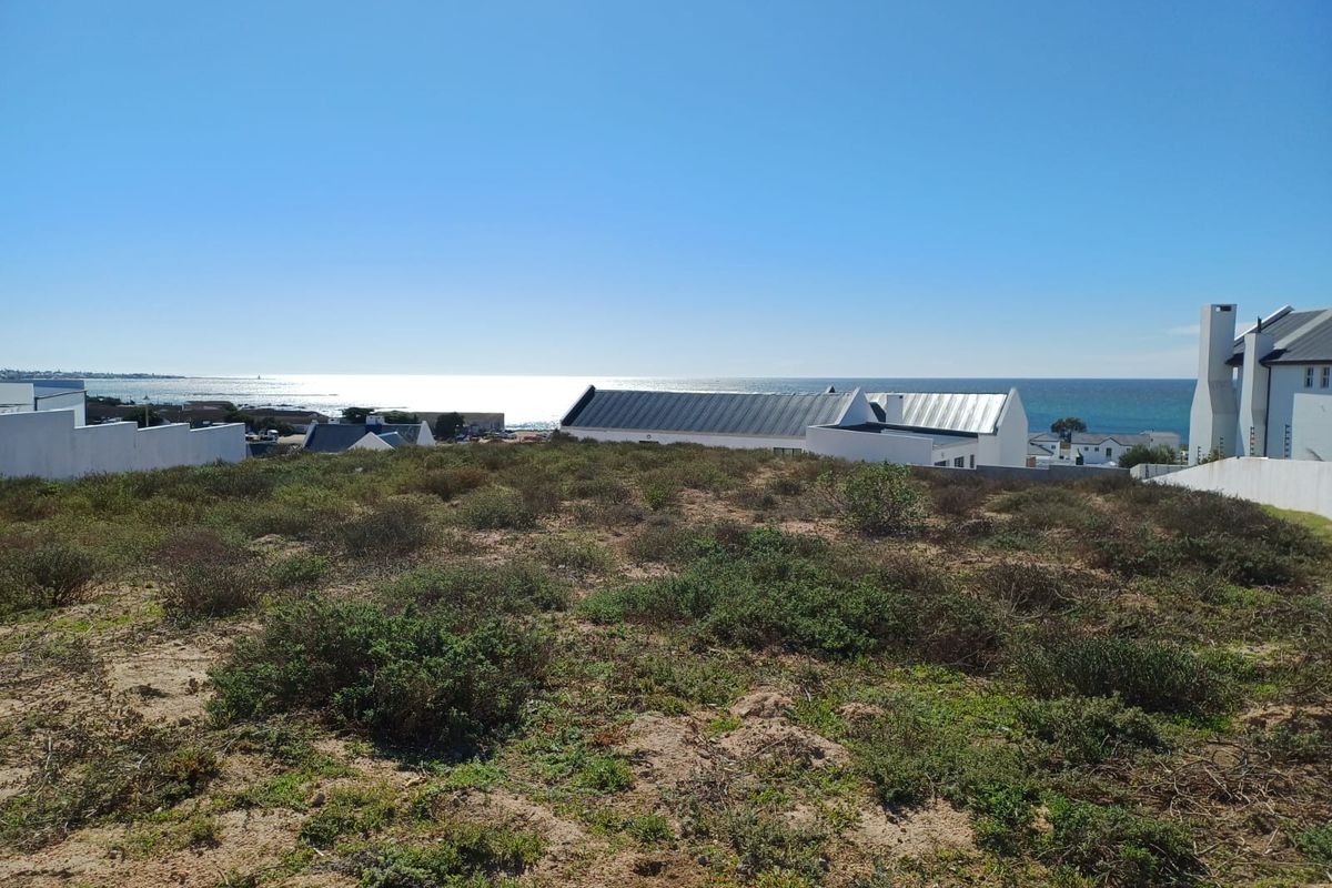 A vacant residential plot offering expansive ocean views, situated in a coastal neighborhood with surrounding established properties.