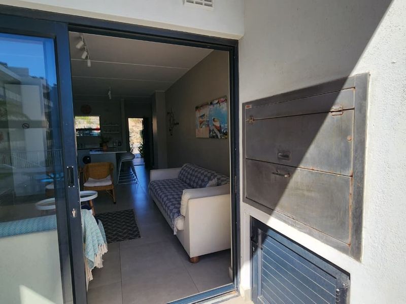 Covered balcony area featuring a built-in braai and sliding glass door access to the open-plan living space.