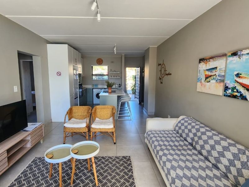 An open-plan living and kitchen area featuring neutral wall tones, tiled flooring, and a functional kitchen island layout.