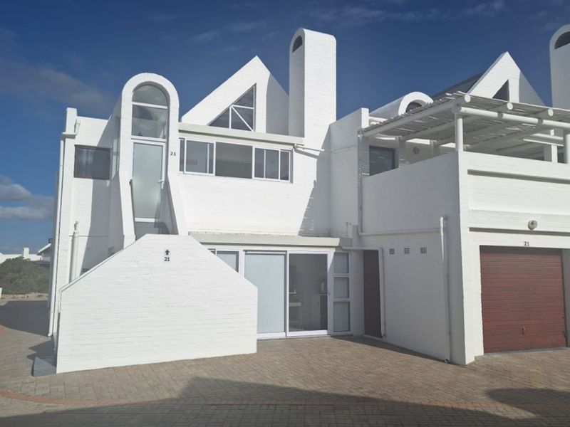 Front elevation of a modern white apartment building featuring a paved driveway, integrated garage, and upper-level balcony with architectural chimney details.