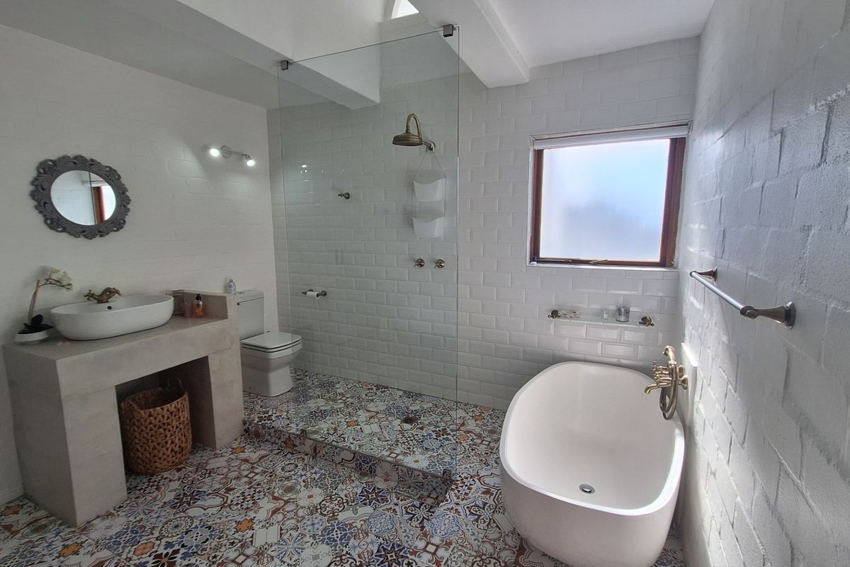 Modern bathroom featuring a freestanding bathtub, walk-in shower with glass screen, vessel sink on a built-in vanity, and stylish patterned floor tiles.