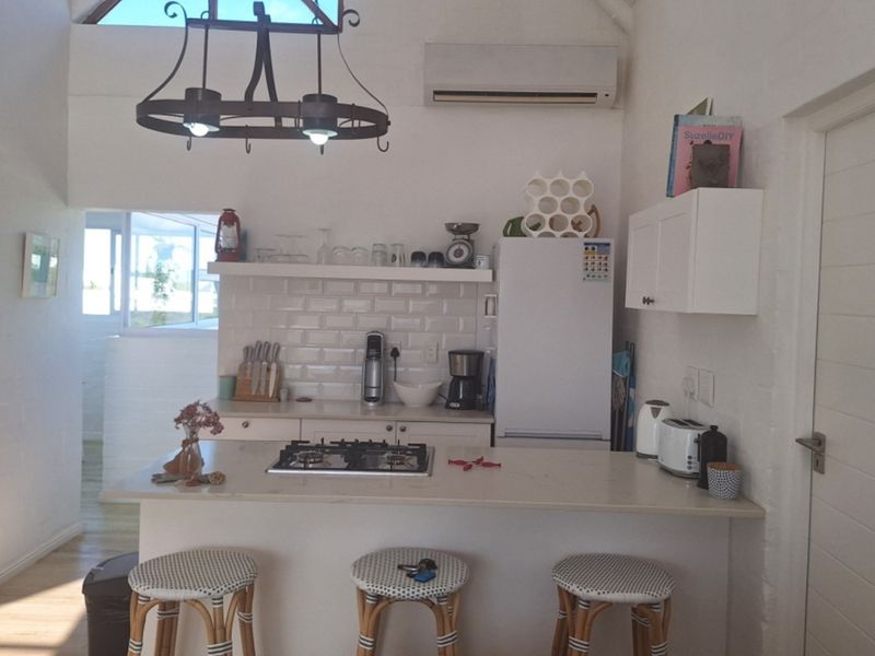 A bright kitchen featuring a central island with a gas hob, subway tile backsplash, and ample built-in cabinetry under a vaulted ceiling.