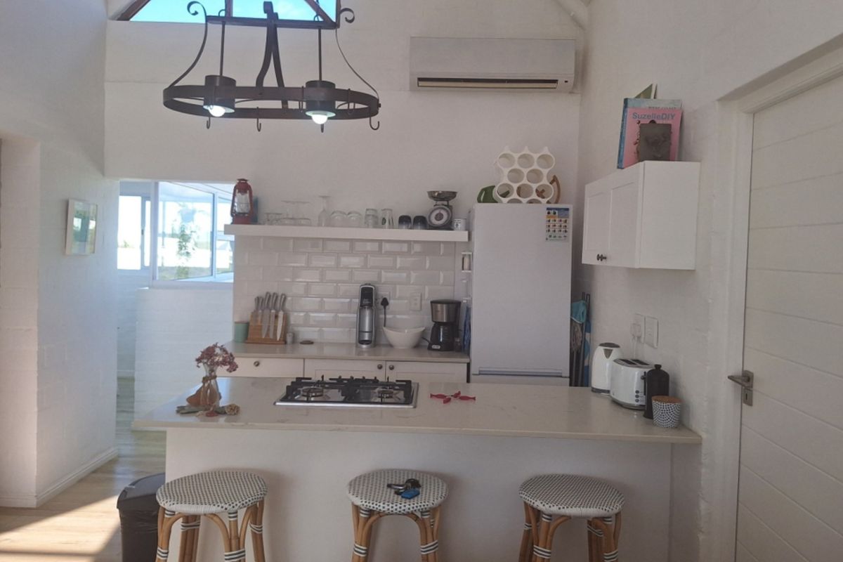 A bright kitchen featuring a central island with a gas hob, subway tile backsplash, and ample built-in cabinetry under a vaulted ceiling.