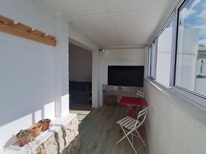 Enclosed balcony featuring a built-in fireplace, stone cladding accents, and sliding windows, providing a versatile outdoor living space.