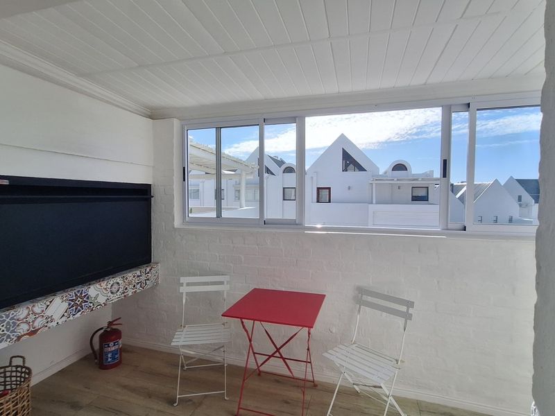 Enclosed balcony or sunroom featuring a built-in fireplace, painted brick walls, and large sliding windows with views of the surrounding complex.