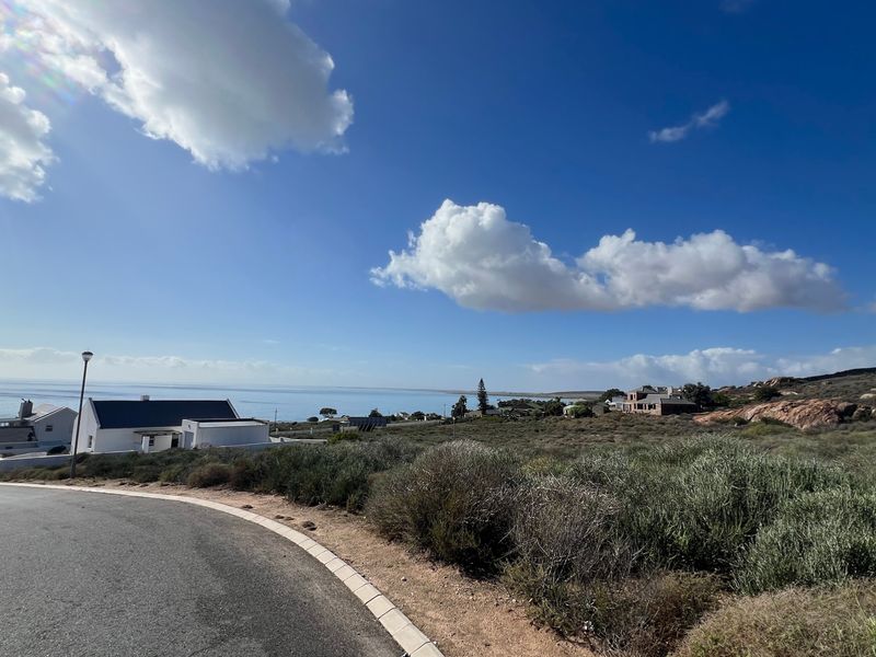 A scenic view of the coastal landscape and surrounding residential area from the paved street level.