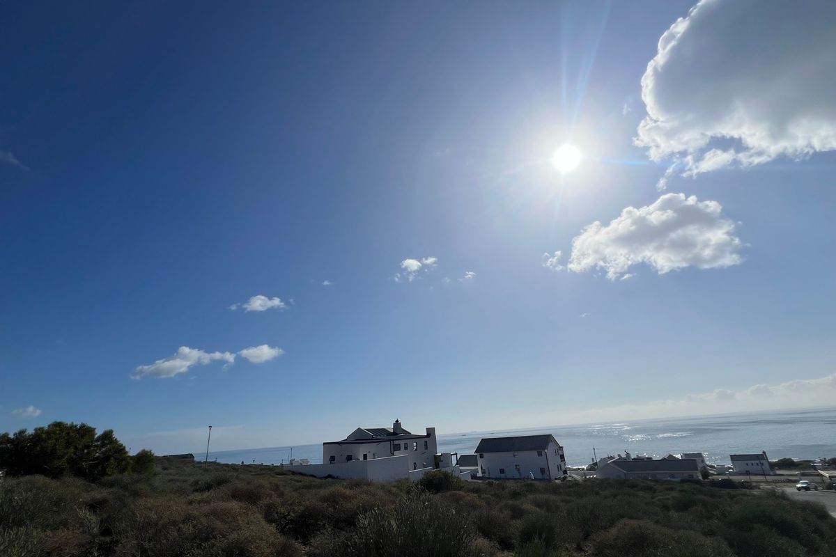 A scenic coastal view overlooking the ocean and surrounding residential properties from an elevated position.