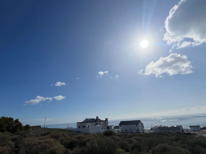 A scenic coastal view overlooking the ocean and surrounding residential properties from an elevated position.