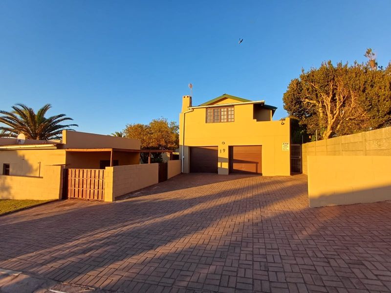 Front view of a residential property featuring a double garage, paved driveway, and secure boundary walling.