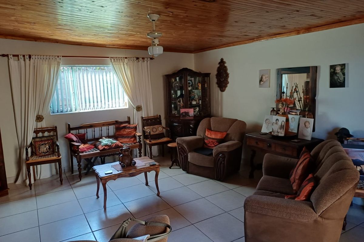 A living room featuring a timber-clad ceiling, tiled flooring, and a central ceiling fan, offering a traditional aesthetic with potential for modern updates.