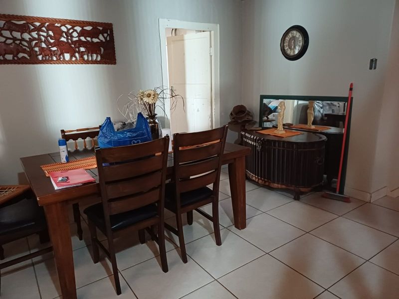 A dining room area featuring ceramic floor tiles and neutral wall finishes, providing a functional space for family meals.