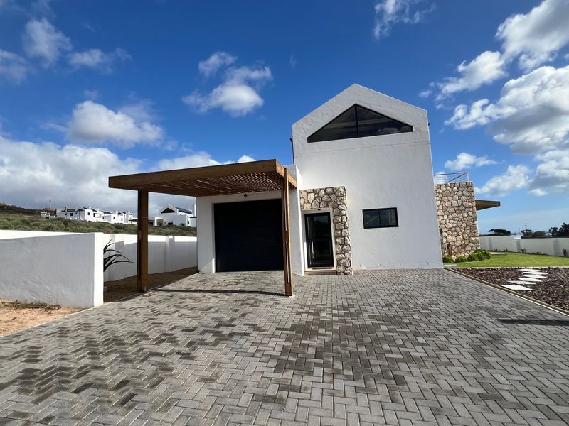 Modern front elevation featuring a paved driveway, timber pergola, stone cladding accents, and a distinctive triangular gable window.