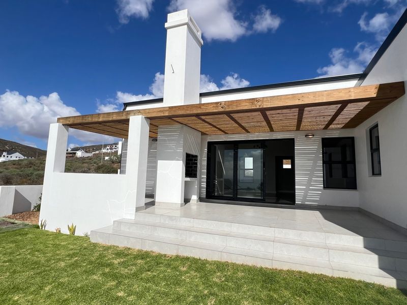 A modern covered patio featuring a timber pergola, built-in braai, and tiled flooring, providing seamless indoor-outdoor flow through large sliding glass doors.
