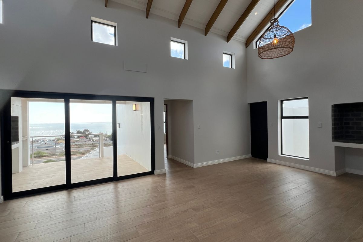 Spacious open-plan living area featuring vaulted ceilings with exposed timber rafters, large sliding doors leading to a balcony, and a built-in fireplace.