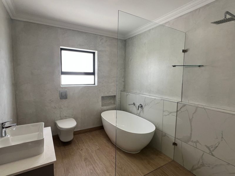 Modern bathroom featuring a freestanding bathtub, glass-enclosed shower, wall-hung toilet, and contemporary vessel sink with high-quality finishes.