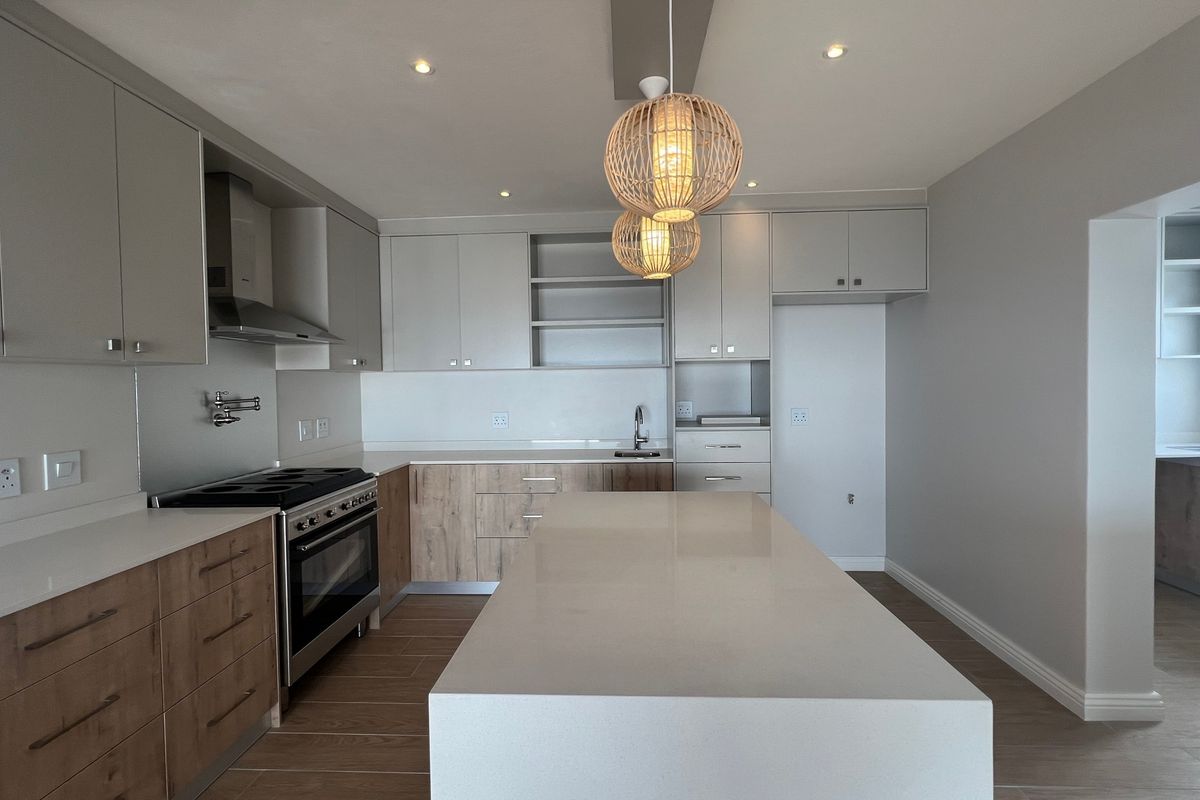 Modern kitchen featuring a large central island, quartz countertops, two-tone cabinetry, and high-quality stainless steel appliances in a bright, open-plan layout.