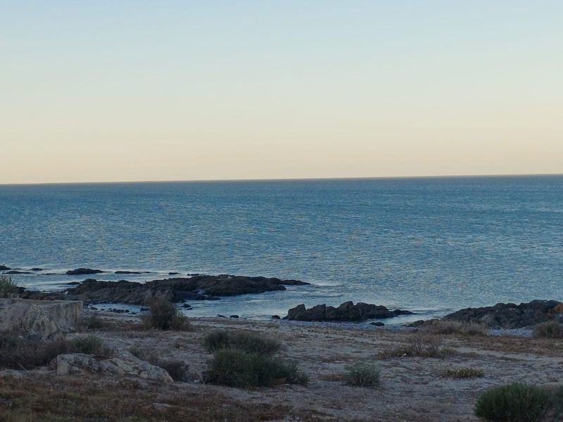 A scenic view of the ocean coastline featuring rocky outcrops and natural vegetation, highlighting the property's coastal location.