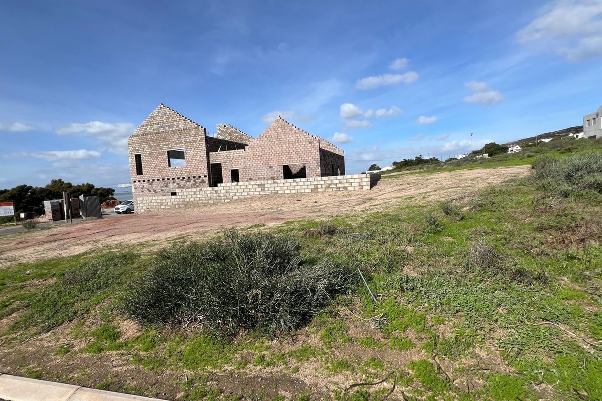 A vacant residential plot featuring an unfinished concrete block structure under construction, offering a blank canvas for development.