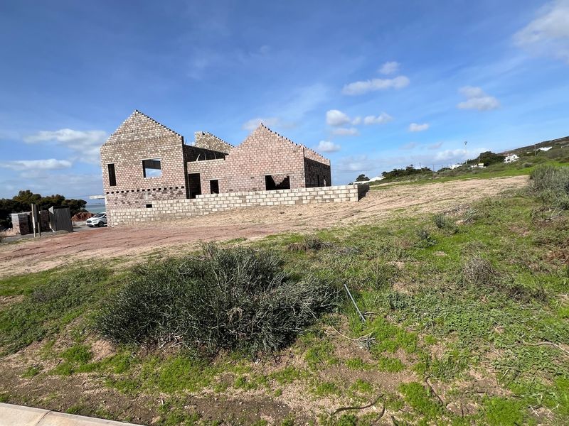A vacant residential plot featuring an unfinished concrete block structure under construction, offering a blank canvas for development.
