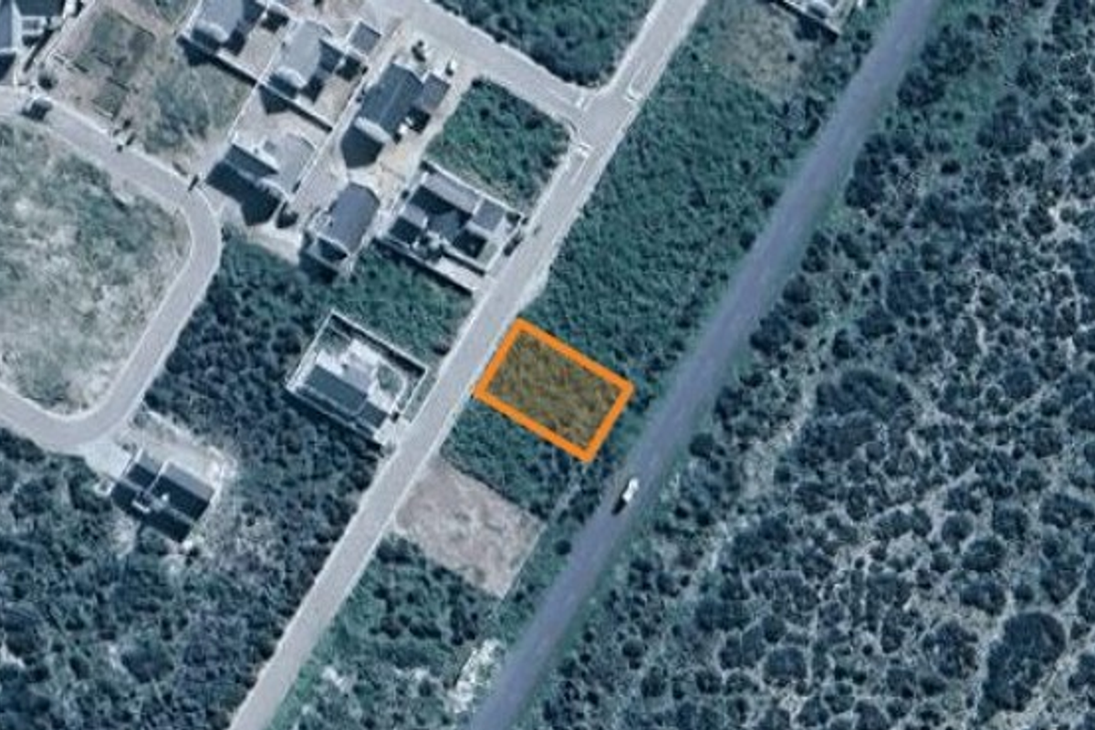 An aerial view showing a vacant residential plot highlighted in orange, situated within a developing neighbourhood.