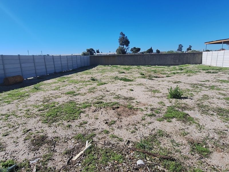 A vacant residential plot featuring a level surface enclosed by precast concrete boundary walls.