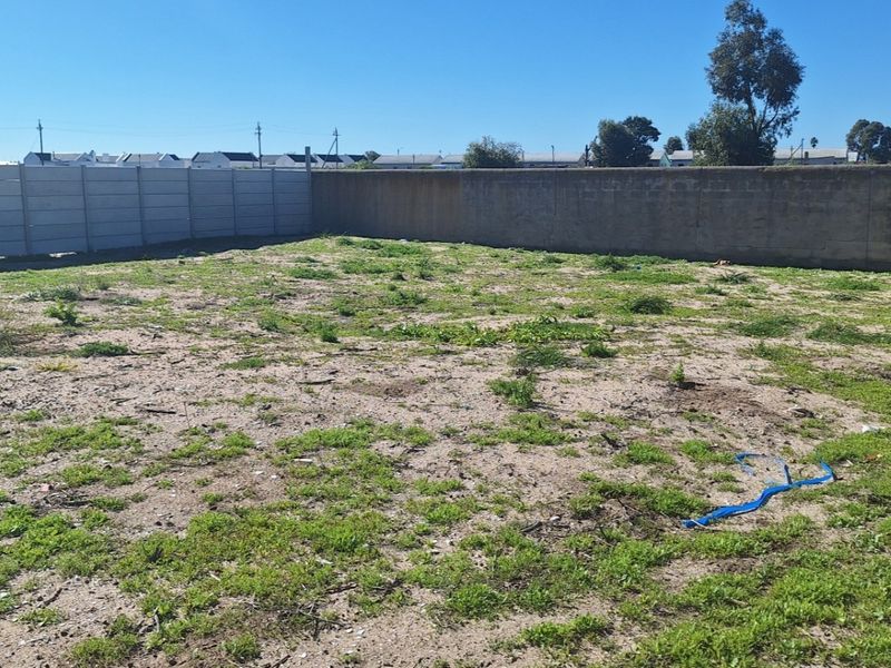 A vacant residential plot featuring perimeter boundary walls and an unimproved, natural ground surface.