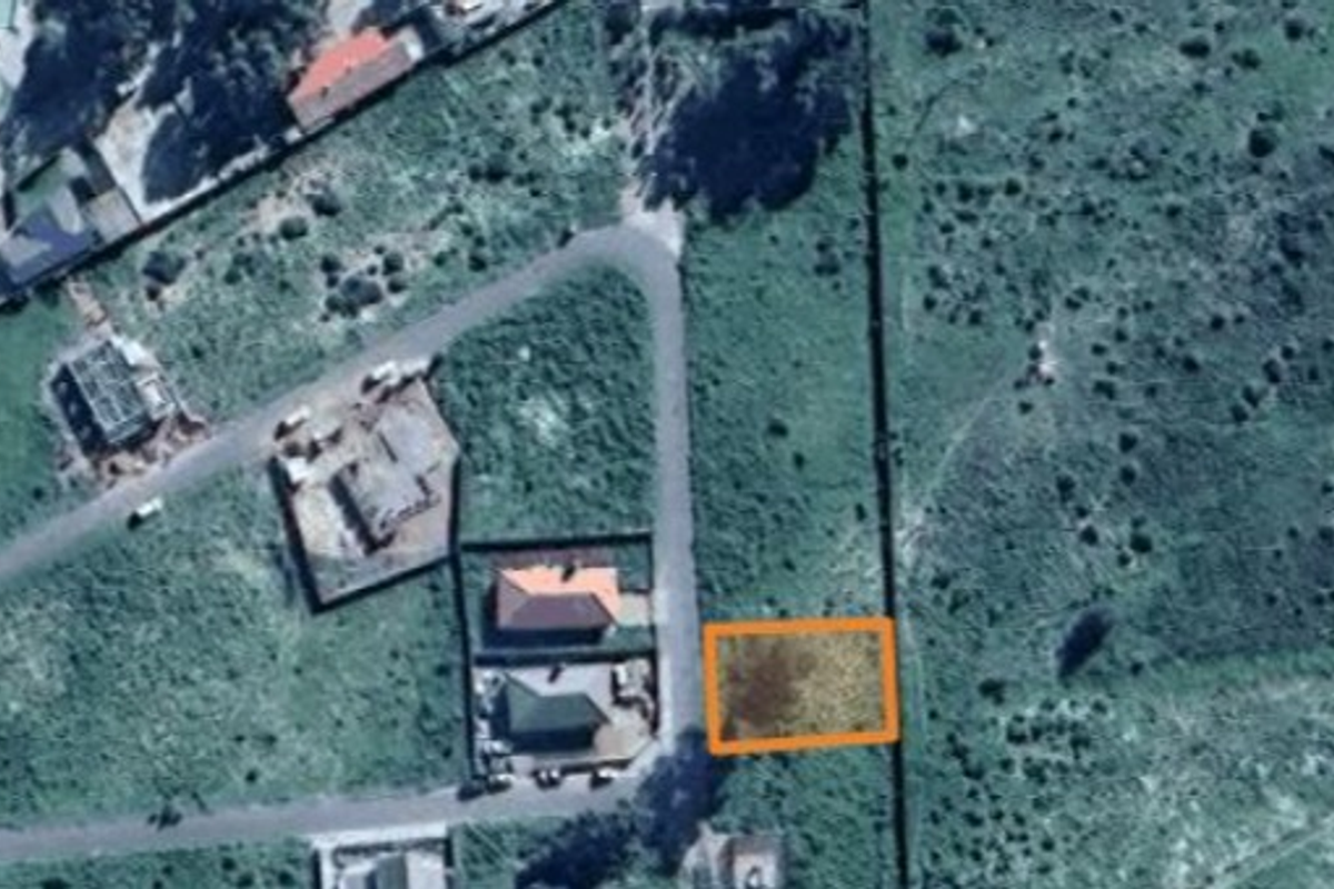 An aerial view of a vacant residential land plot situated within a developed neighborhood with established road access.