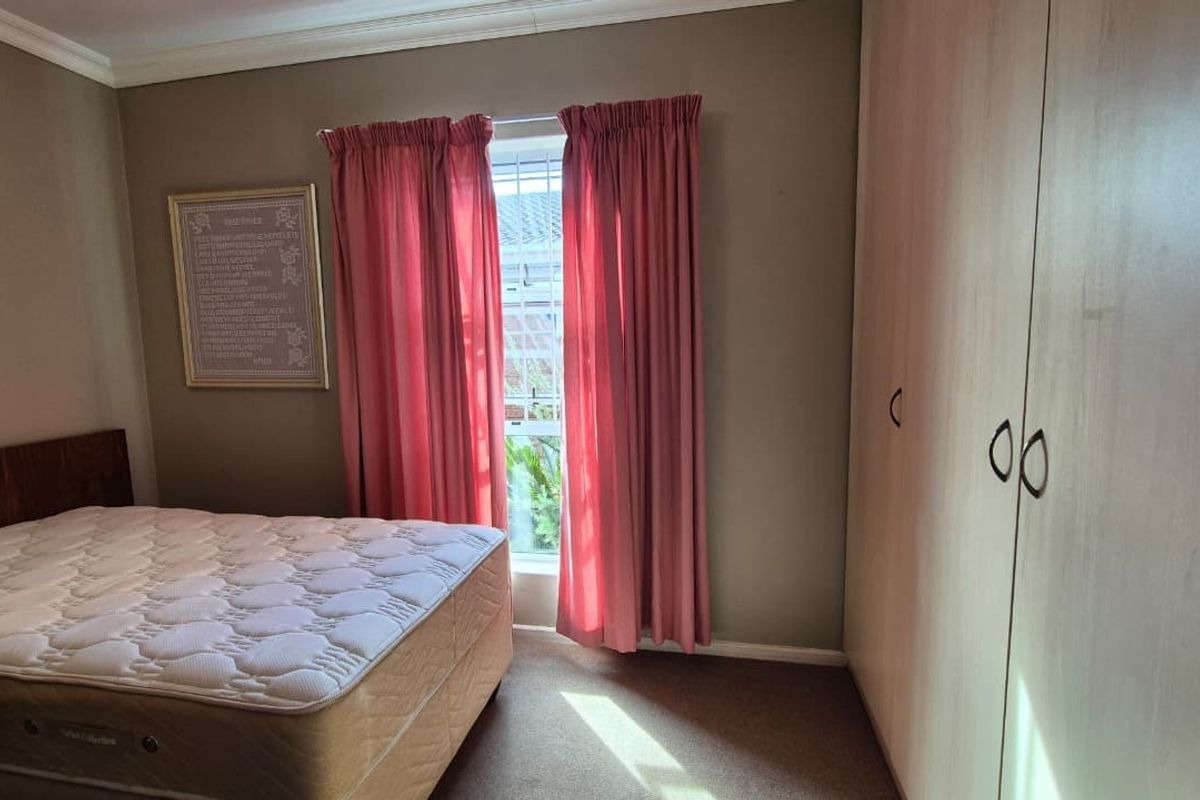 A bedroom featuring built-in cupboards, crown molding, and carpeted flooring, providing a functional space within the retirement village.