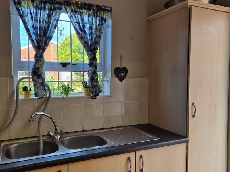 Functional kitchen area featuring a double bowl stainless steel sink, laminate countertops, and built-in cabinetry with a window overlooking the exterior.
