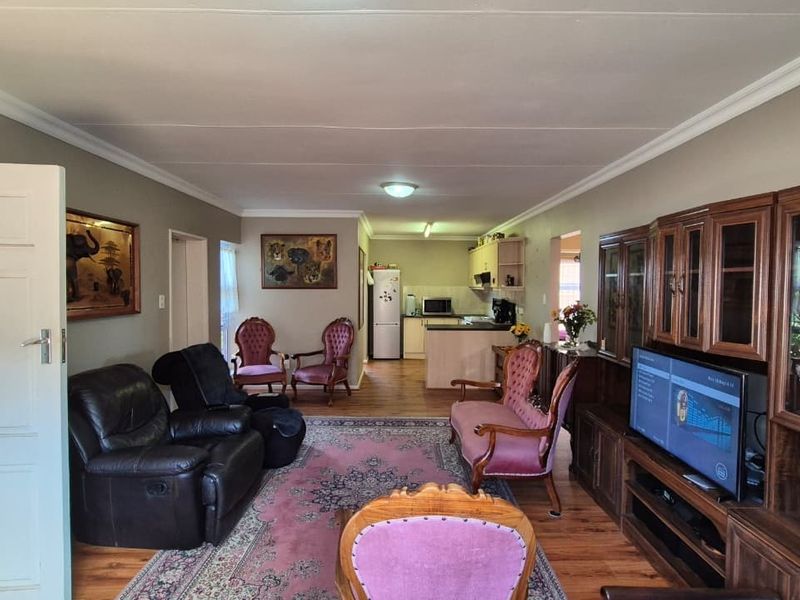 Open-plan living and dining area featuring laminate flooring, coved ceilings, and a functional kitchen with built-in cabinetry and a peninsula.