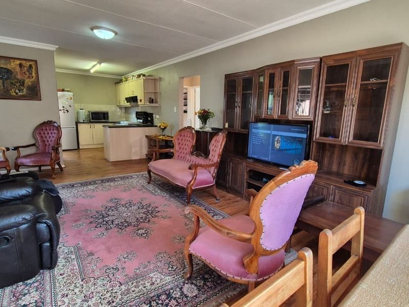 Open plan living area featuring laminate flooring and a connected kitchen with built-in cabinetry and an extractor fan.