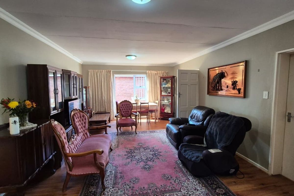A spacious living room featuring laminate flooring, coved ceilings, and neutral wall tones, offering a comfortable and functional layout for relaxation.
