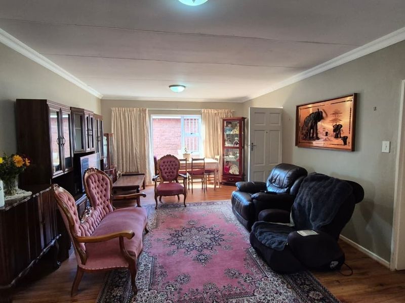 A spacious living room featuring laminate flooring, coved ceilings, and neutral wall tones, offering a comfortable and functional layout for relaxation.